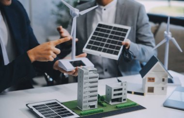 İki Genç Mühendis Güneş Hücresi Kurulum Toplantısı ve İş Tartışması Uzmanı. Ofis Odası 'nda Fabrika İnşaat Planlı Çatı Üzerine Güneş Fotovoltaik Panelleri Kurmayı Planlıyorum.