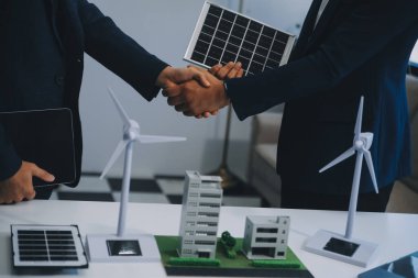 İki Genç Mühendis Güneş Hücresi Kurulum Toplantısı ve İş Tartışması Uzmanı. Ofis Odası 'nda Fabrika İnşaat Planlı Çatı Üzerine Güneş Fotovoltaik Panelleri Kurmayı Planlıyorum.