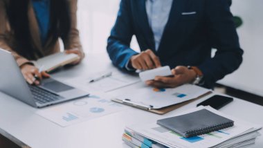 İş ekibi ile yeni başlangıç planı ve tartışma için proje bilgilerini dizüstü bilgisayar ve dijital tablet ile mali strateji bir modern iş salonda çalışıyor.