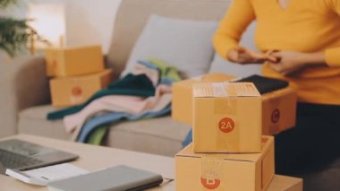vlogger, blog yazarı küçük KOBİ iş kadını Asyalı güzel kadınlar kıyafetleri canlı yayın satışı internet üzerinden satışı, ev ofisinde mevcut ürün detaylarını gösterme, girişimci ekommerce