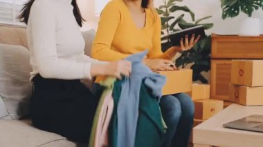 vlogger, blog yazarı küçük KOBİ iş kadını Asyalı güzel kadınlar kıyafetleri canlı yayın satışı internet üzerinden satışı, ev ofisinde mevcut ürün detaylarını gösterme, girişimci ekommerce