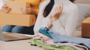 vlogger, blog yazarı küçük KOBİ iş kadını Asyalı güzel kadınlar kıyafetleri canlı yayın satışı internet üzerinden satışı, ev ofisinde mevcut ürün detaylarını gösterme, girişimci ekommerce