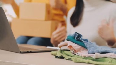 Genç bir kadın, müşterisine teslim etmek için giysilerini topluyor. çevrimiçi alışveriş.