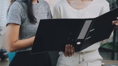 İki genç Asyalı iş kadını yeni başlatılan proje sunumuyla ilgili konuşuyor, tartışıyor, görüşüyorlar. Plan pazarlama ve ofis yatırımlarını analiz ediyorlar..