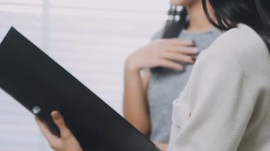 İki genç Asyalı iş kadını yeni başlatılan proje sunumuyla ilgili konuşuyor, tartışıyor, görüşüyorlar. Plan pazarlama ve ofis yatırımlarını analiz ediyorlar..