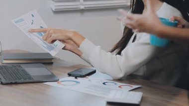 İki genç Asyalı iş kadını yeni başlatılan proje sunumuyla ilgili konuşuyor, tartışıyor, görüşüyorlar. Plan pazarlama ve ofis yatırımlarını analiz ediyorlar..