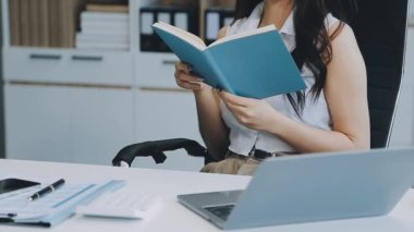 Ofiste oturan Asyalı kadın, hesap makinesi, veriler, çizelgeler ve dokümanlar üzerinde çalışıyor.. 