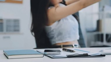 Ofiste oturan Asyalı kadın, hesap makinesi, veriler, çizelgeler ve dokümanlar üzerinde çalışıyor.. 
