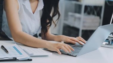 Ofiste oturan Asyalı kadın, hesap makinesi, veriler, çizelgeler ve dokümanlar üzerinde çalışıyor.. 