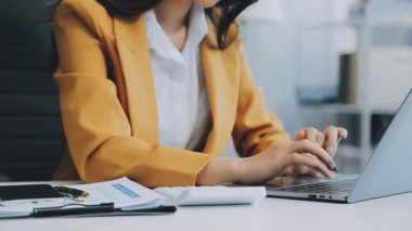 Ofiste oturan Asyalı kadın, hesap makinesi, veriler, çizelgeler ve dokümanlar üzerinde çalışıyor.. 