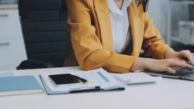 Ofiste oturan Asyalı kadın, hesap makinesi, veriler, çizelgeler ve dokümanlar üzerinde çalışıyor.. 