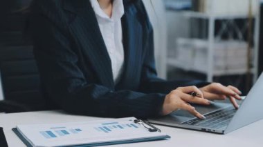 Ofiste oturan Asyalı kadın, hesap makinesi, veriler, çizelgeler ve dokümanlar üzerinde çalışıyor.. 