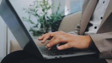 Profesyonel olarak giyinmiş bir işadamı, son teknoloji ve sofistike dekorasyonun üretkenliğini artırdığı modern ve şık bir ofiste aktif olarak dizüstü bilgisayarı üzerinde çalışıyor.