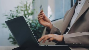 Kredi kartı tutan ve alışveriş merkezinde dizüstü bilgisayar kullanan bir iş adamı. çevrimiçi bankacılık ve ödeme kavramı.