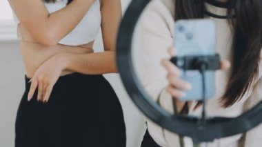 Genç bayan arkadaşlar kameranın önünde video çekiyor.