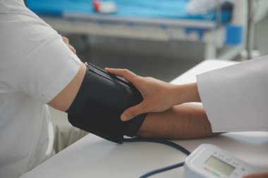 Erkek doktor, check-up, tıbbi tedavi ve sağlık konsepti için hastaneye gelen hastaların vücut basıncını ve nabzını ölçmek için kan basıncı monitörü kullanır..