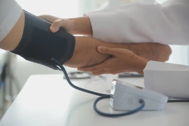 Erkek doktor, check-up, tıbbi tedavi ve sağlık konsepti için hastaneye gelen hastaların vücut basıncını ve nabzını ölçmek için kan basıncı monitörü kullanır..