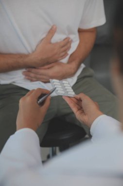 Şiddetli mide ağrısı çeken bir adam evde oturuyor. Karnı ağrıyan, ishal ya da hazımsızlık çeken bir adamın eli. Kafkasyalı adam, acı verici bir şekilde karnına bastırıyor.