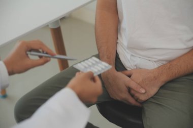 Erkek hastalıkları. Adam ellerini kasıklarına bastırıyor ve acı çekiyor. Panorama, kesilmiş, stüdyo çekimi.