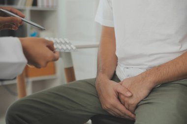 Erkek hastalıkları. Adam ellerini kasıklarına bastırıyor ve acı çekiyor. Panorama, kesilmiş, stüdyo çekimi.