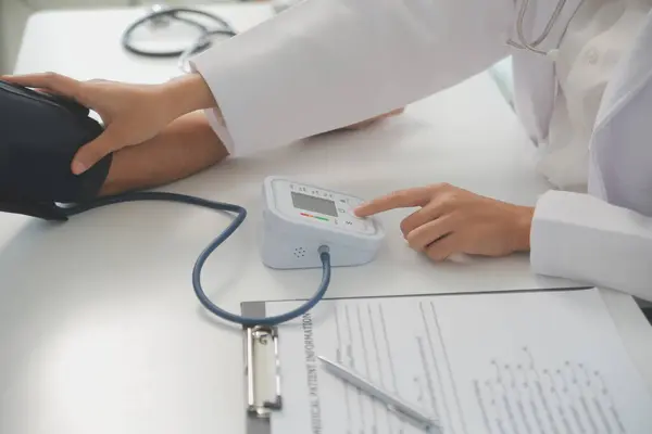 Erkek doktor, check-up, tıbbi tedavi ve sağlık konsepti için hastaneye gelen hastaların vücut basıncını ve nabzını ölçmek için kan basıncı monitörü kullanır..