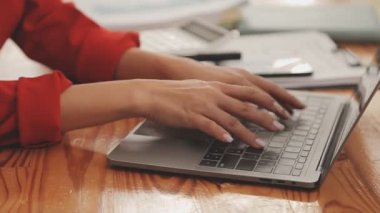 Kırmızı takım elbiseli güzel Asyalı bir kadının portresi modern ofiste dizüstü bilgisayarda çalışıyor.