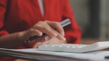 Genç bir iş kadını, iş ve finans kavramlarını ön plana çıkaran bir fon ile çağdaş bir ofiste çalışırken resmedilir..