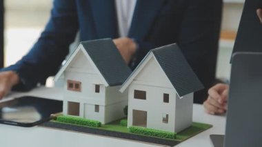 Emlakçının elinde model ev modeli ve arka planda anahtar var. gerçek sigorta kavramı.