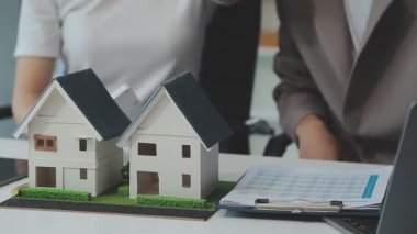 Emlakçı ve müşteriyle ev modeli satın alma, sigorta ya da kredi alma ya da emlak ya da mülkiyet sözleşmesi hakkında tartışıyor.