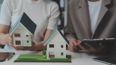 Emlakçı ve müşteriyle ev modeli satın alma, sigorta ya da kredi alma ya da emlak ya da mülkiyet sözleşmesi hakkında tartışıyor.