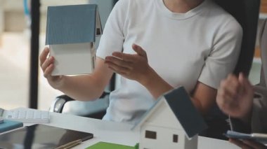 Emlakçı ve müşteriyle ev modeli satın alma, sigorta ya da kredi alma ya da emlak ya da mülkiyet sözleşmesi hakkında tartışıyor.