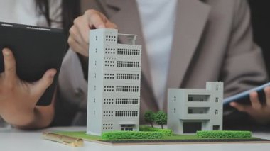 Emlakçı ve müşteriyle ev modeli satın alma, sigorta ya da kredi alma ya da emlak ya da mülkiyet sözleşmesi hakkında tartışıyor.