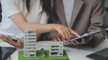 Emlakçı ve müşteriyle ev modeli satın alma, sigorta ya da kredi alma ya da emlak ya da mülkiyet sözleşmesi hakkında tartışıyor.