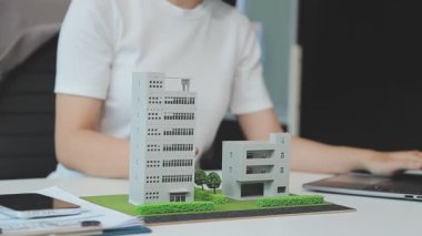 Emlakçı ve müşteriyle ev modeli satın alma, sigorta ya da kredi alma ya da emlak ya da mülkiyet sözleşmesi hakkında tartışıyor.