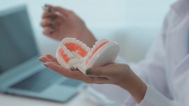Diş hekimi, diş modelini, diş hijyenini, tablet x-ray teknolojisini, ortodontist uzmanı muayenehanesini inceleyen bir doktor.