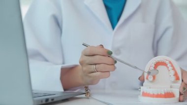 Diş hekimi, diş modelini, diş hijyenini, tablet x-ray teknolojisini, ortodontist uzmanı muayenehanesini inceleyen bir doktor.