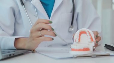 Diş hekimi, diş modelini, diş hijyenini, tablet x-ray teknolojisini, ortodontist uzmanı muayenehanesini inceleyen bir doktor.