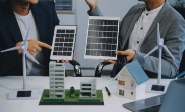 İki Genç Mühendis Güneş Hücresi Kurulum Toplantısı ve İş Tartışması Uzmanı. Ofis Odası 'nda Fabrika İnşaat Planlı Çatı Üzerine Güneş Fotovoltaik Panelleri Kurmayı Planlıyorum.