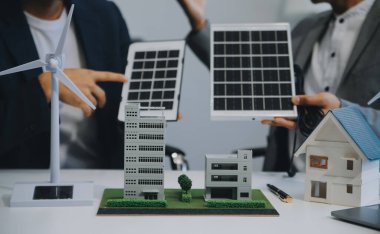 İki Genç Mühendis Güneş Hücresi Kurulum Toplantısı ve İş Tartışması Uzmanı. Ofis Odası 'nda Fabrika İnşaat Planlı Çatı Üzerine Güneş Fotovoltaik Panelleri Kurmayı Planlıyorum.