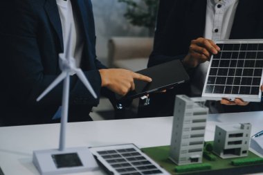 İki Genç Mühendis Güneş Hücresi Kurulum Toplantısı ve İş Tartışması Uzmanı. Ofis Odası 'nda Fabrika İnşaat Planlı Çatı Üzerine Güneş Fotovoltaik Panelleri Kurmayı Planlıyorum.