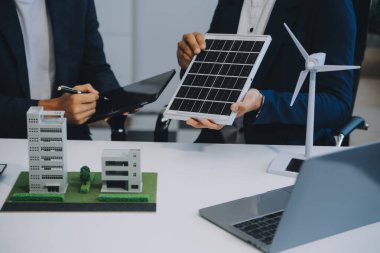 İki Genç Mühendis Güneş Hücresi Kurulum Toplantısı ve İş Tartışması Uzmanı. Ofis Odası 'nda Fabrika İnşaat Planlı Çatı Üzerine Güneş Fotovoltaik Panelleri Kurmayı Planlıyorum.