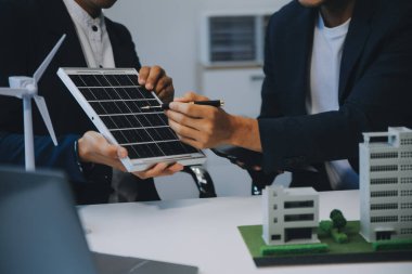 İki Genç Mühendis Güneş Hücresi Kurulum Toplantısı ve İş Tartışması Uzmanı. Ofis Odası 'nda Fabrika İnşaat Planlı Çatı Üzerine Güneş Fotovoltaik Panelleri Kurmayı Planlıyorum.