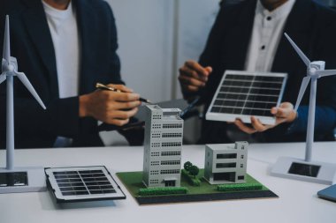 İki Genç Mühendis Güneş Hücresi Kurulum Toplantısı ve İş Tartışması Uzmanı. Ofis Odası 'nda Fabrika İnşaat Planlı Çatı Üzerine Güneş Fotovoltaik Panelleri Kurmayı Planlıyorum.