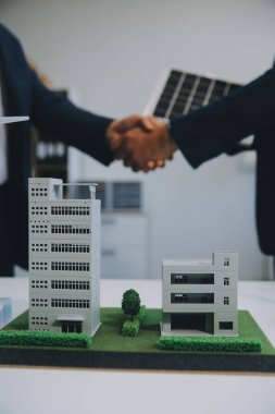 İki Genç Mühendis Güneş Hücresi Kurulum Toplantısı ve İş Tartışması Uzmanı. Ofis Odası 'nda Fabrika İnşaat Planlı Çatı Üzerine Güneş Fotovoltaik Panelleri Kurmayı Planlıyorum.