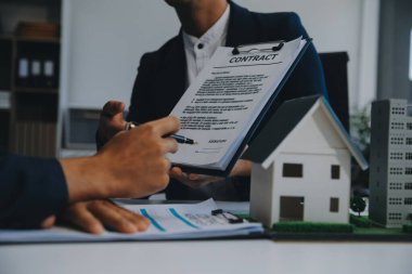 Emlakçı ev satın alma anlaşmasının şartları hakkında konuştu ve müşteriden sözleşmeyi yasal hale getirmek için belgeleri imzalamasını istedi, ev satışları ve ev sigortası kavramı.