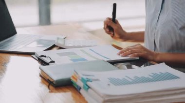 Modern ofiste belgelerle çalışan genç iş kadını, hızlı iş ve finans dünyasını yansıtıyor..