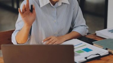 Modern ofiste belgelerle çalışan genç iş kadını, hızlı iş ve finans dünyasını yansıtıyor..