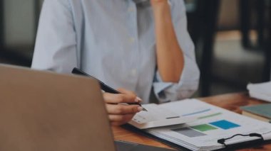 Modern ofiste belgelerle çalışan genç iş kadını, hızlı iş ve finans dünyasını yansıtıyor..