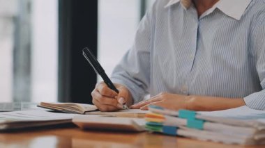 Modern ofiste belgelerle çalışan genç iş kadını, hızlı iş ve finans dünyasını yansıtıyor..