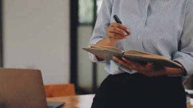 Genç bir iş kadını, bir iş ve finans temasını yansıtan çağdaş ofis ortamında çalışmalarına odaklanmış..